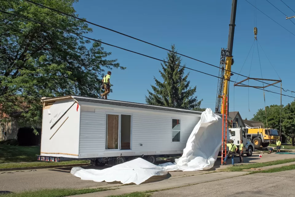 White modular home being installed on a lot.